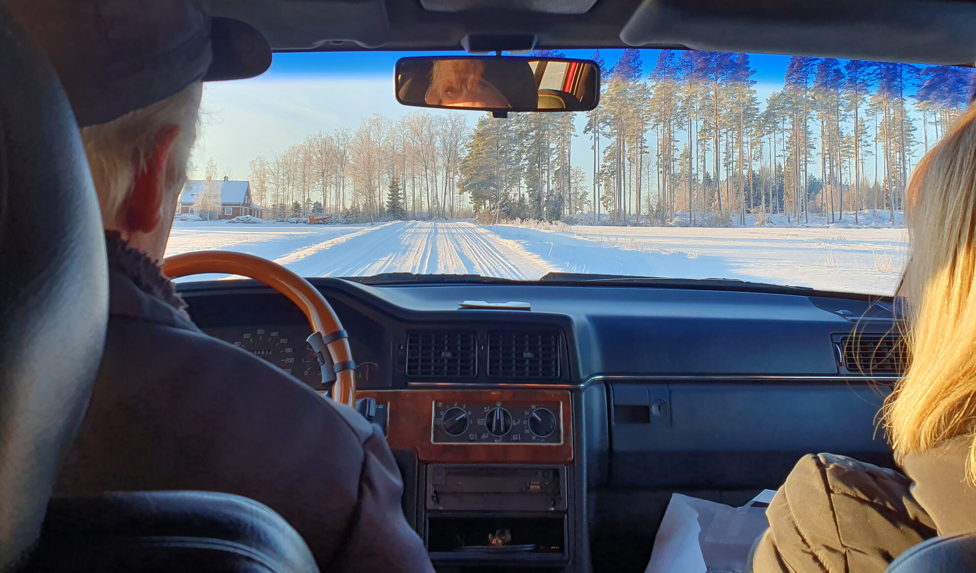 Plogad väg i snöigt landskap sedd inifrån bilen