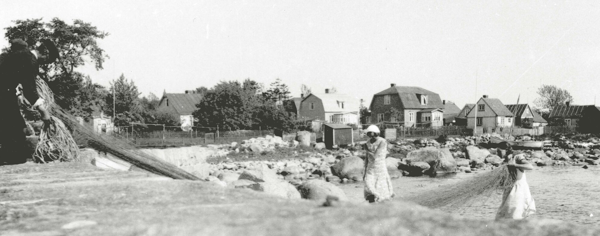 Två kvinnor och en man hanterar ett fiskenät.