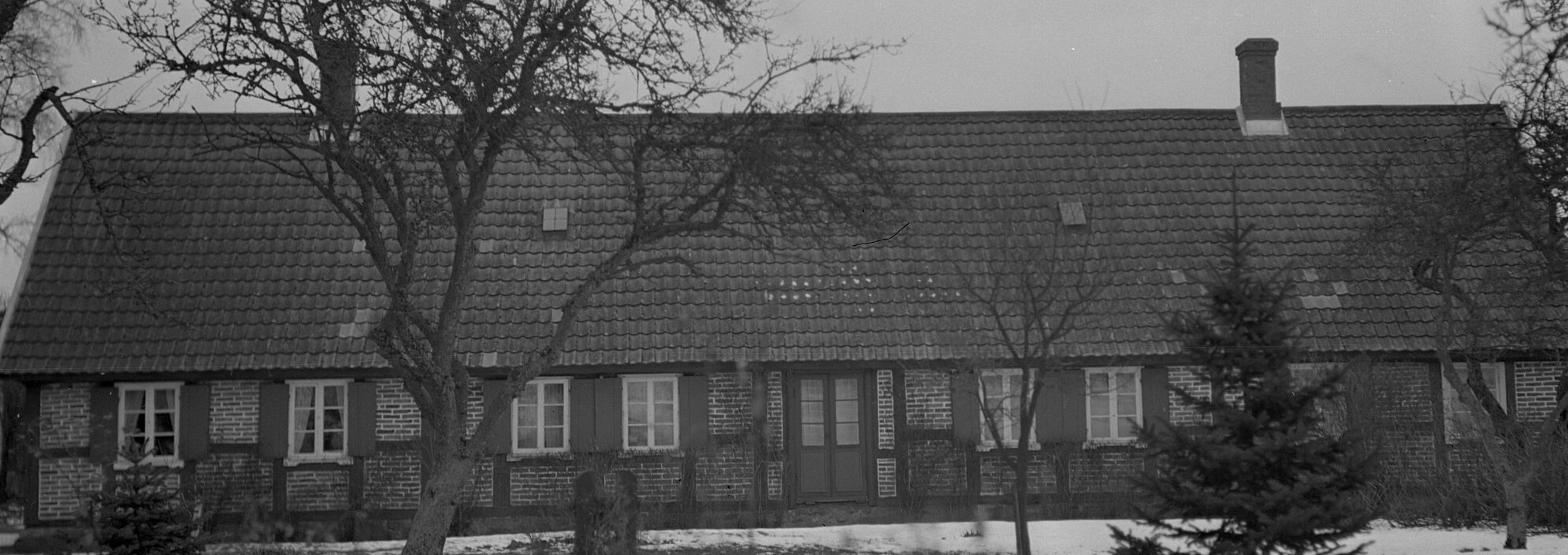 En husfasad med trädgård i förgrunden.